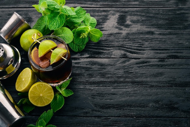 Cuba libre cocktailglas Lime mint Op een zwarte houten ondergrond Vrije ruimte voor tekst