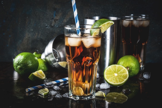 Photo cuba libre, long island or iced tea cocktail with strong alcohol, cola, lime and ice, two glass, dark