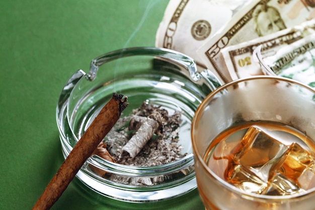 Cuban cigar and money on green surface