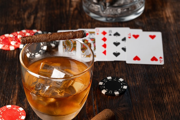 Bicchiere di whisky di sigaro cubano e patatine sul tavolo