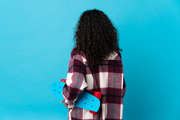 Cuban woman isolated on blue with a skate in back position