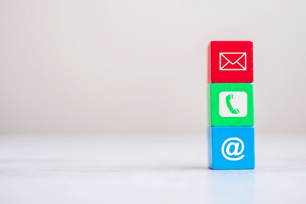 Cube block with email, telephone and address website symbol on table background