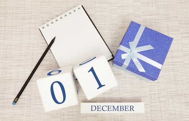 Cube calendar for December 1 and gift box, near a notebook with a pencil
