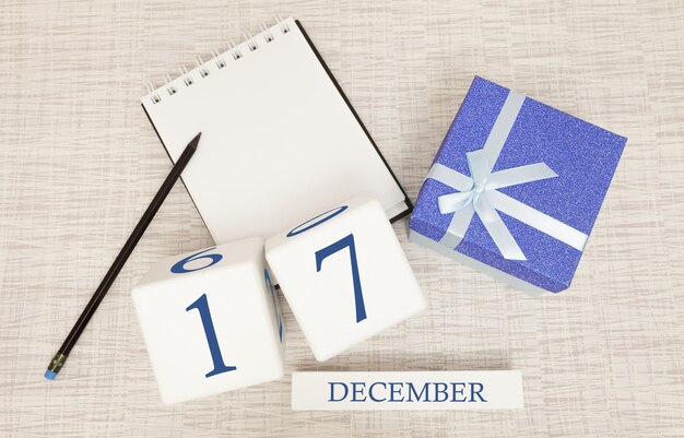 Cube calendar for December 17 and gift box, near a notebook with a pencil