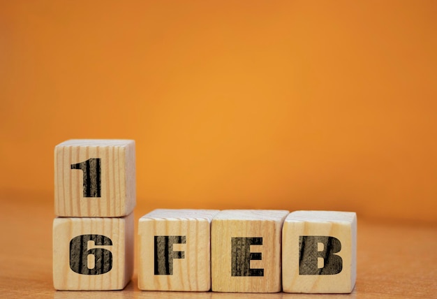 Cube shape calendar for february 16 on wooden surface with empty space for text new year wooden calendar with date february cube calendar on wooden surface with copy space