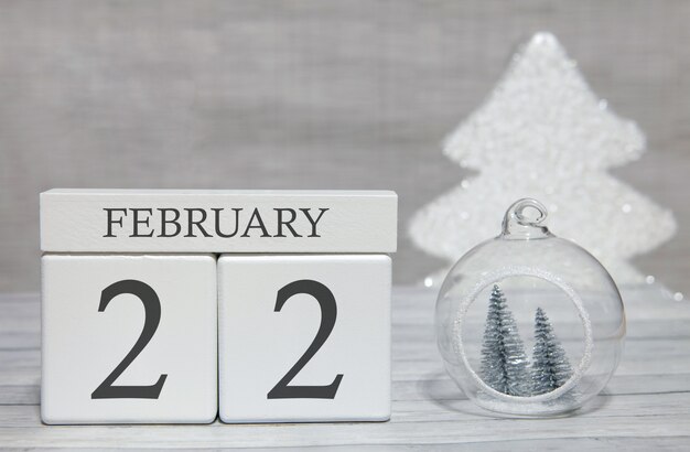 Cube shape calendar for February 22 on wooden surface and light background