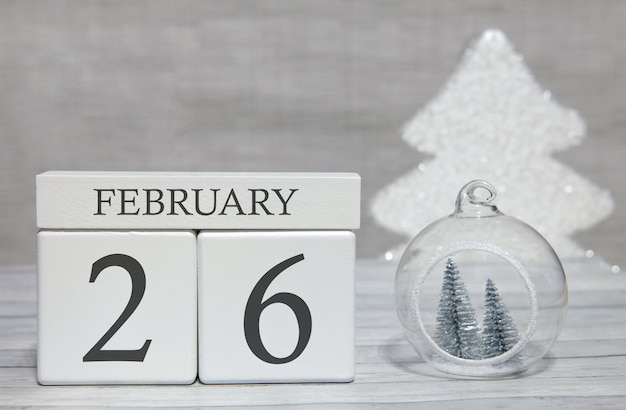 Cube shape calendar for February 26 on wooden surface and light background