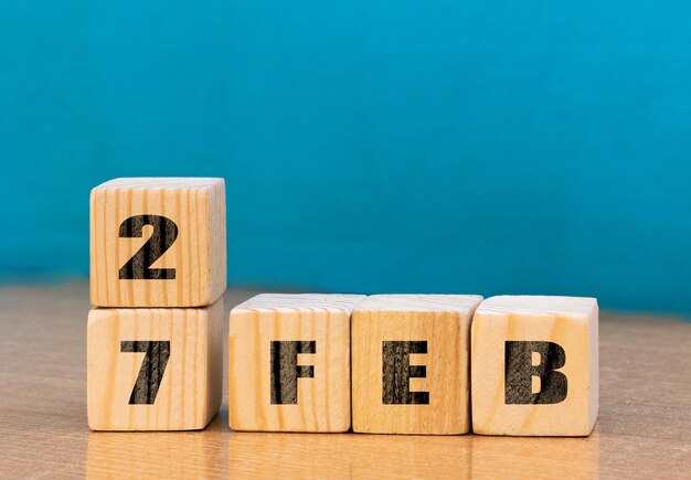 テキストキューブカレンダー用の空きスペースを持つ木製の表面に2月27日のキューブ形状のカレンダー