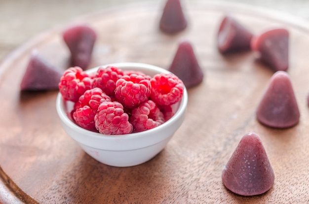 Cuberdons with fresh raspberries on the wooden board