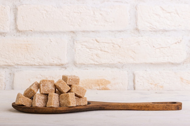 Cubes of crushed cane sugar in a wooden spoon