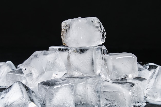 Cubi di ghiaccio dall'acqua con foglie di menta su uno sfondo nero.