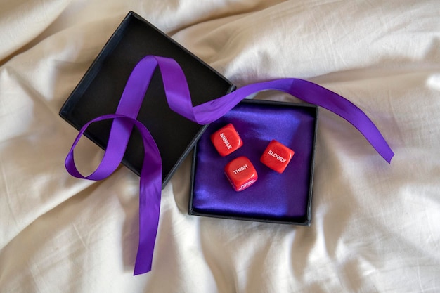 Cubes for sex games in the black box with purple ribbon. Sexy romantic gift. Playing cubes