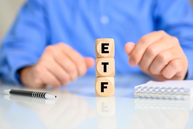 Кубики с буквами, составляющими слово ETF с мужчиной на заднем плане