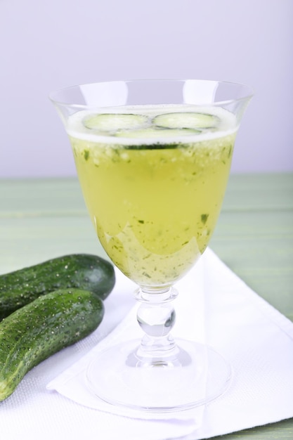 Cucumber cocktail on napkin on wooden table on light background