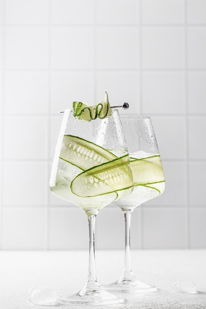 Foto acqua disintossicante infusa di cetriolo in bicchieri con ghiaccio limonata aromatizzata fatta in casa su bianco grigio