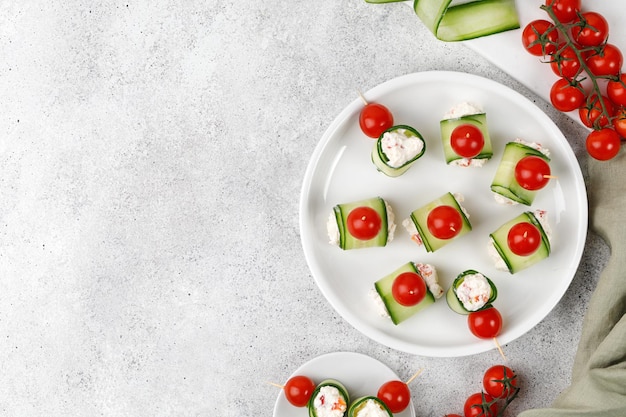 Cucumber rolls stuffed with cream cheese served on a white plate Holiday snack canapes