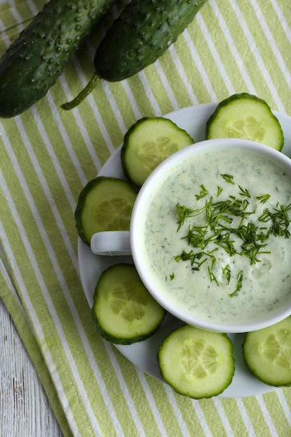 Foto zuppa di cetriolo in ciotola sullo sfondo di tavolo in legno colorato