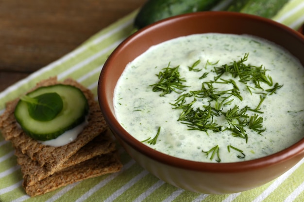 Cucumber soup in bowl on rustic wooden table background