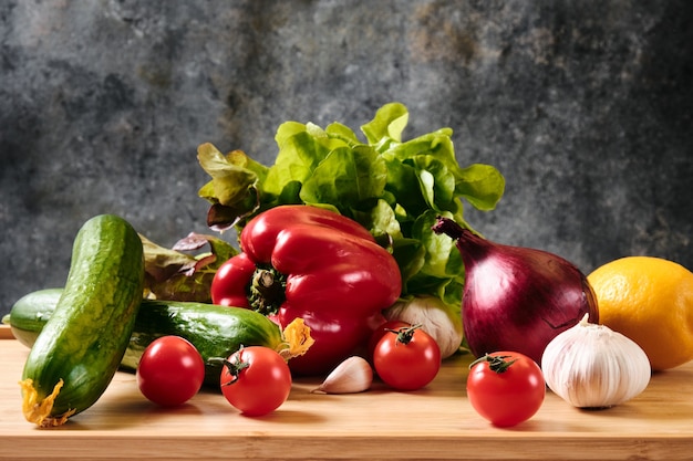 Cucumber, tomatoes, peppers, garlic and lettuce on a dark background