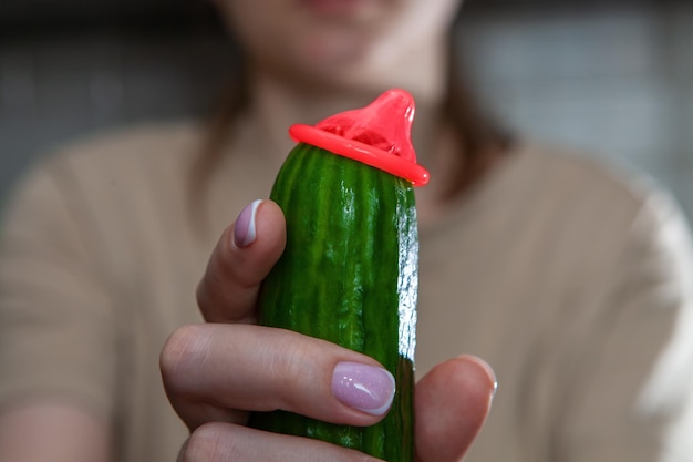 Cucumber with a condomWoman holding a cucumber with a condom Sex education