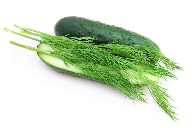 A cucumber with the cut half lying on a dill