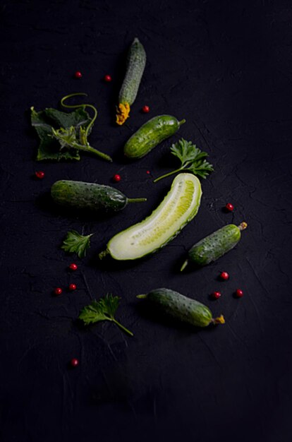 Cucumbers gherkins and leaves on a black background blurred image