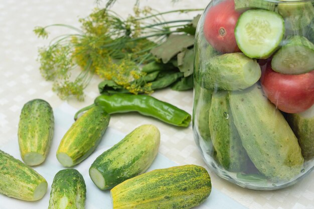 テーブルの上にピーマンとキュウリとピクルス野菜のキュウリとトマトとハーブとスパイスを保存用に準備したガラス瓶付き 選択と集中 収穫秋の準備