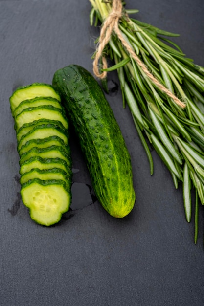 cucumbers with a sprig of rosemary on a black table