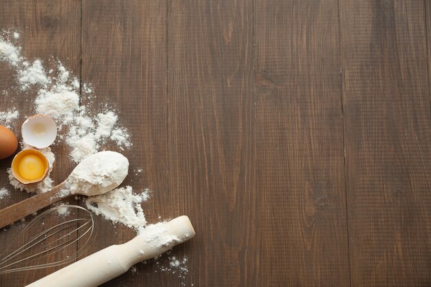 Cuisine composition with cracked eggs,kitchenware, flour. View from above