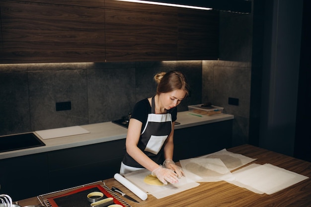 Culinair koken eten en mensen concept gelukkig lachende jonge vrouw deeg rollen en broodjes bakken op keuken thuis