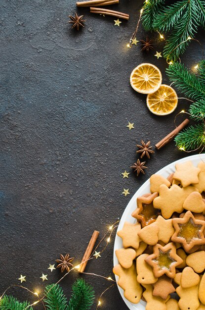 Culinaire achtergrond met vers gebakken kerstmispeperkoek, kruiden en dennentakken.