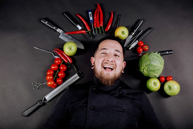 Culinaire achtergrond met verse rauwe groenten en keukengerei op een zwarte achtergrond