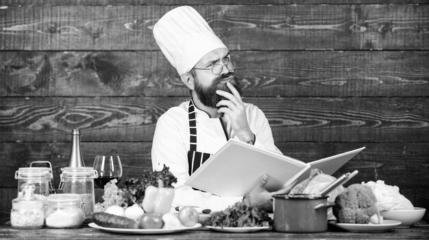 Photo culinary arts concept man learn recipe try something new cookery on my mind improve cooking skill book recipes according to recipe man bearded chef cooking food guy read book recipes