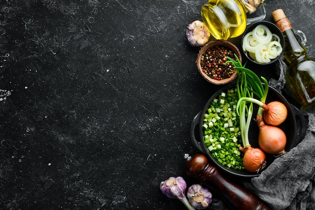 Culinary background Onions garlic and spices on a black stone background Top view