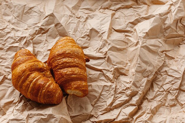 Culinary background Two croissants close up on a brown paper background