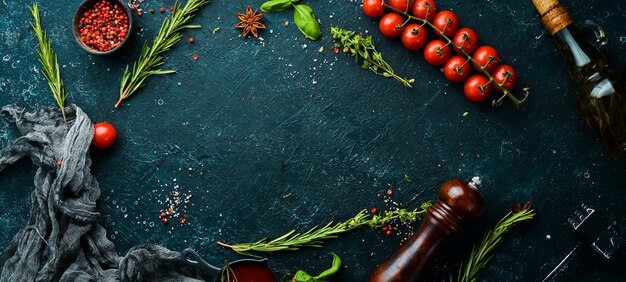 Culinary banner Cherry tomatoes rosemary spices and herbs on a black stone background Top view Rustic style