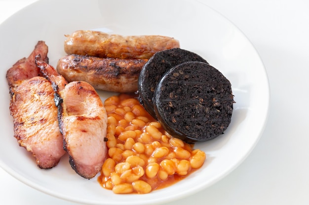 Cumberland sausages back bacon baked beans and black pudding in a white bowl