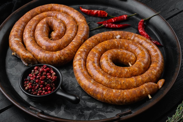 Foto cumberland worst spiraal varkensworst op zwarte houten tafel achtergrond