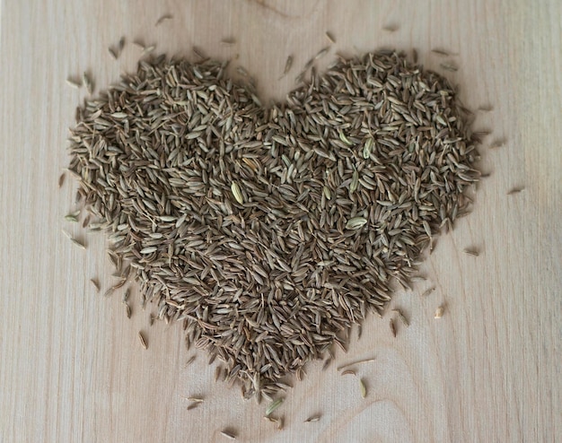 Cumin lined in the shape of a heart on a wooden table Zira spice