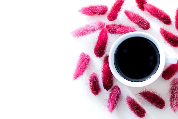 Cup of aromatic black espresso coffee isolated on white background surrounded by a set of dry pink autumn flowers