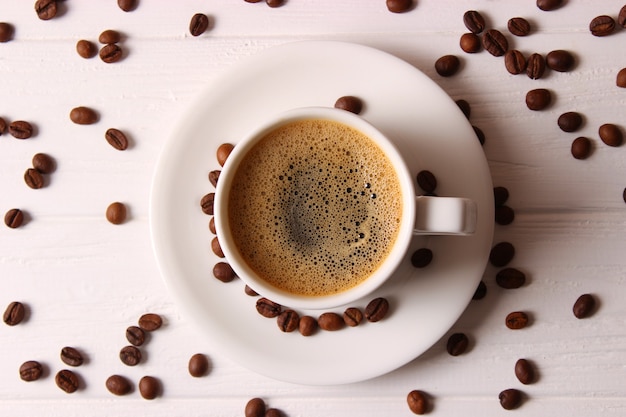 Чашка ароматного кофе и кофейных зерен на деревянном фоне. Фото высокого качества