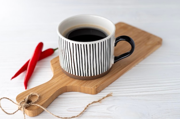 흰색 배경에 있는 향기로운 뜨거운 블랙 커피 한 잔과 붉은 급성 후추