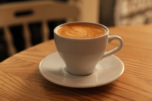カフェのクローズ アップで木製のテーブルに香りのよいホット コーヒーのカップ
