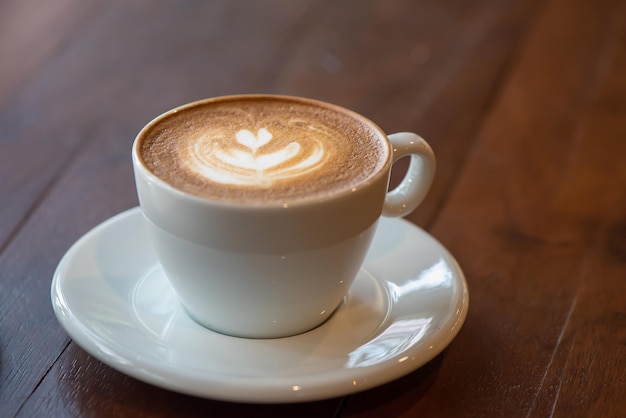 Cup of art latte or cappuccino coffee on wood table