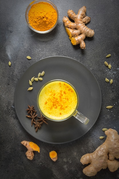 Cup of ayurvedic golden turmeric latte milk with curcuma powder and anise star