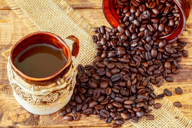 Cup of black coffee and beans on wooden background