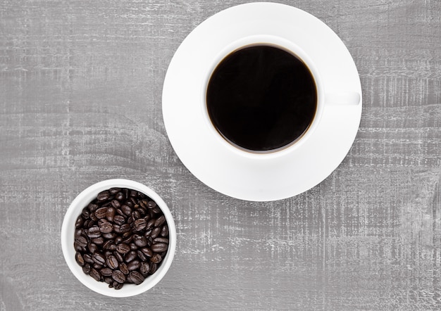 Чашка черного кофе на завтрак с фасолью на поверхности кофейных зерен