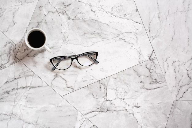 A cup of black coffee and glasses on a marble tile Pause at work Scandinavian house design