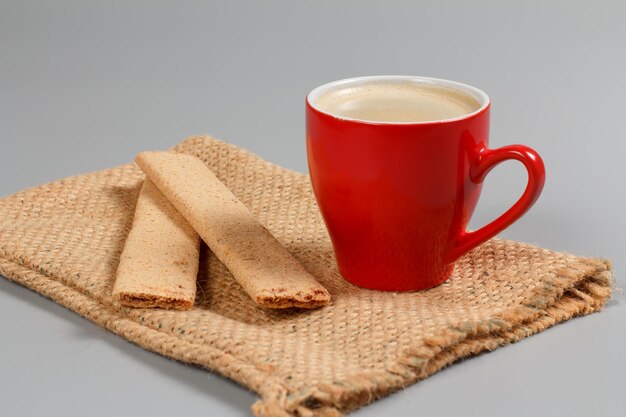 Cup of black coffee and pastry on sackcloth bag