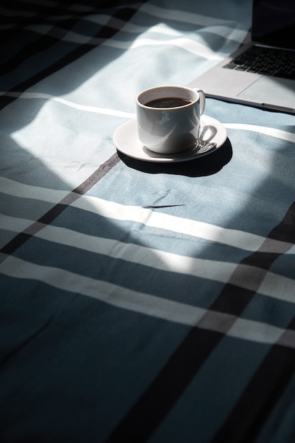 Tazza di caffè nero su un laptop tazza bianca e luce dalla finestra stare a casa